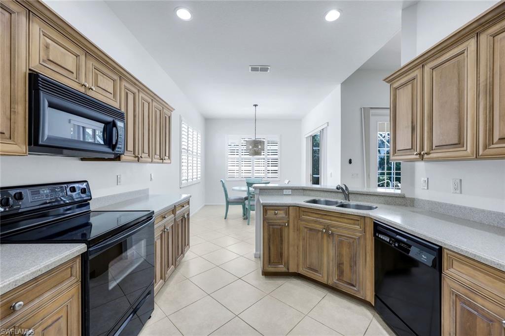 9375 Oak Strand Drive Estero, FL 34135 - Photo 12 of 30 Kitchen with light tile patterned floors, brown cabinets, light countertops, black appliances, and a sink