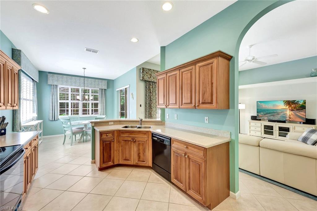 9375 Oak Strand Drive Estero, FL 34135 - Photo 14 of 32 Kitchen with light tile patterned floors, brown cabinets, light countertops, black appliances, and a sink