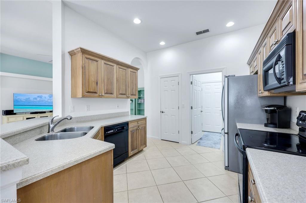 9375 Oak Strand Drive Estero, FL 34135 - Photo 10 of 30 a kitchen with stainless steel appliances granite countertop a sink and a refrigerator
