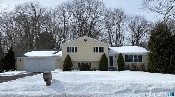 a front view of a house with a yard and large trees
