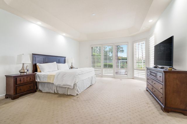 a spacious bedroom with a large bed and a flat tv screen on dresser