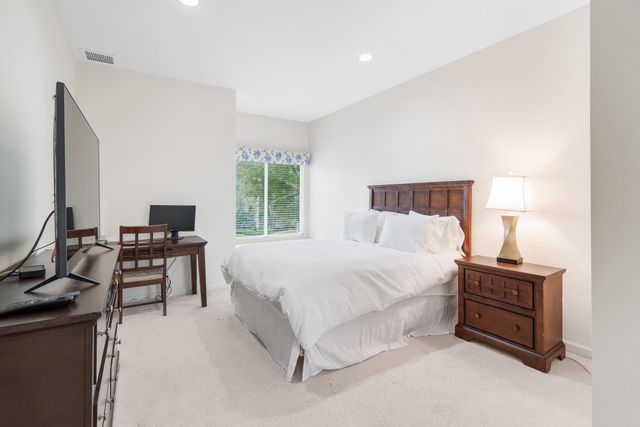 a bedroom with a bed and a computer on the desk next to a window