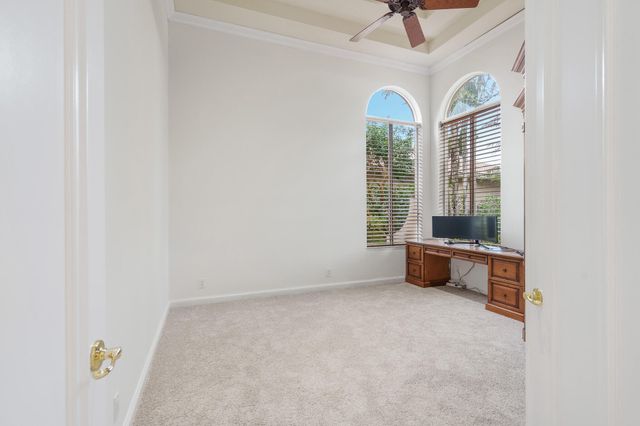 an empty room with windows and ceiling fan