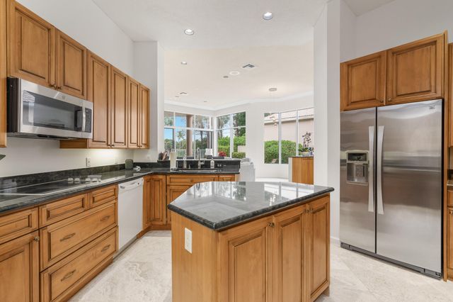 a kitchen with stainless steel appliances granite countertop a refrigerator a stove and a sink with wooden floor