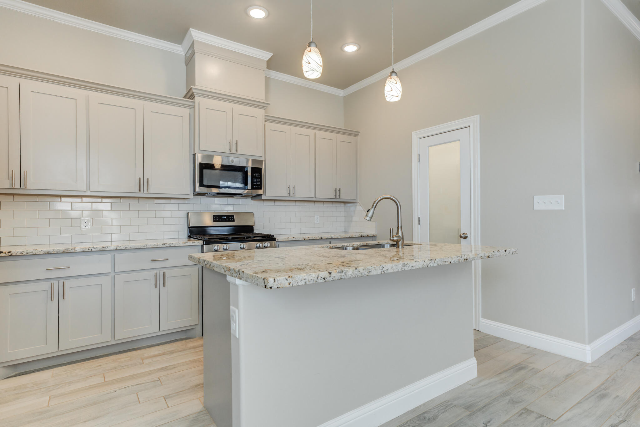 7633 87th Street Lubbock, TX 79424 - Photo 22 of 47 a kitchen with granite countertop a sink and white cabinets
