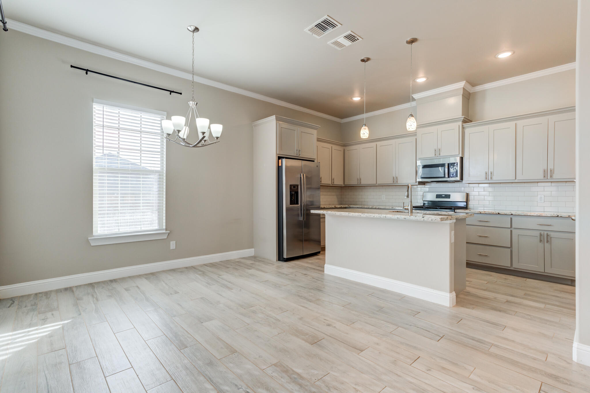 7633 87th Street Lubbock, TX 79424 - Photo 5 of 47 a kitchen with stainless steel appliances granite countertop a refrigerator a sink dishwasher a stove and white cabinets with wooden floor