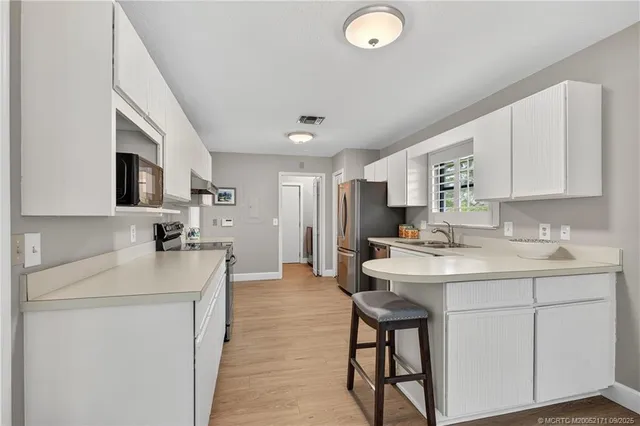 a kitchen with a sink stainless steel appliances and white cabinets