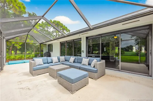a living room with patio furniture and garden view