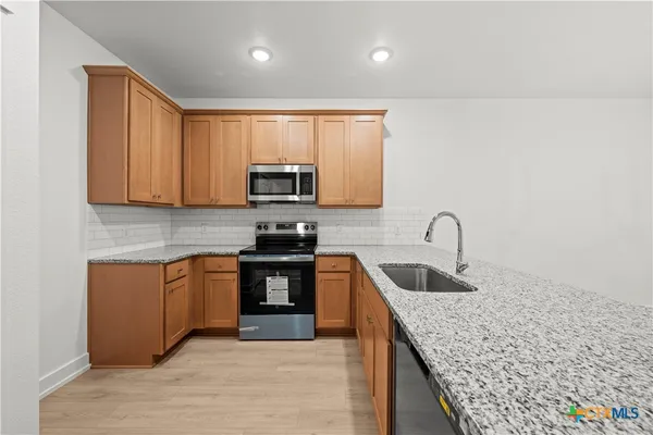 a kitchen with stainless steel appliances granite countertop a sink stove and microwave