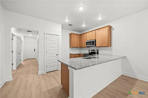 a kitchen with stainless steel appliances granite countertop a sink stove and cabinets