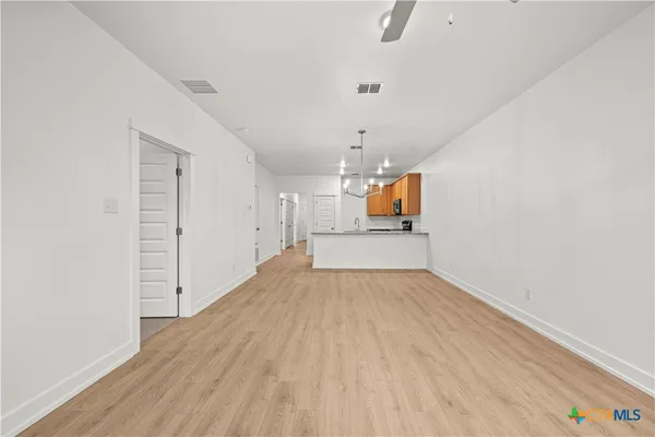 a view of an empty room with a window and wooden floor