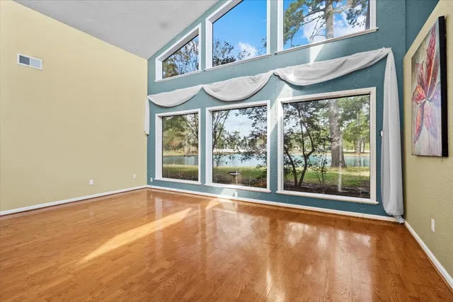an empty room with wooden floor and windows