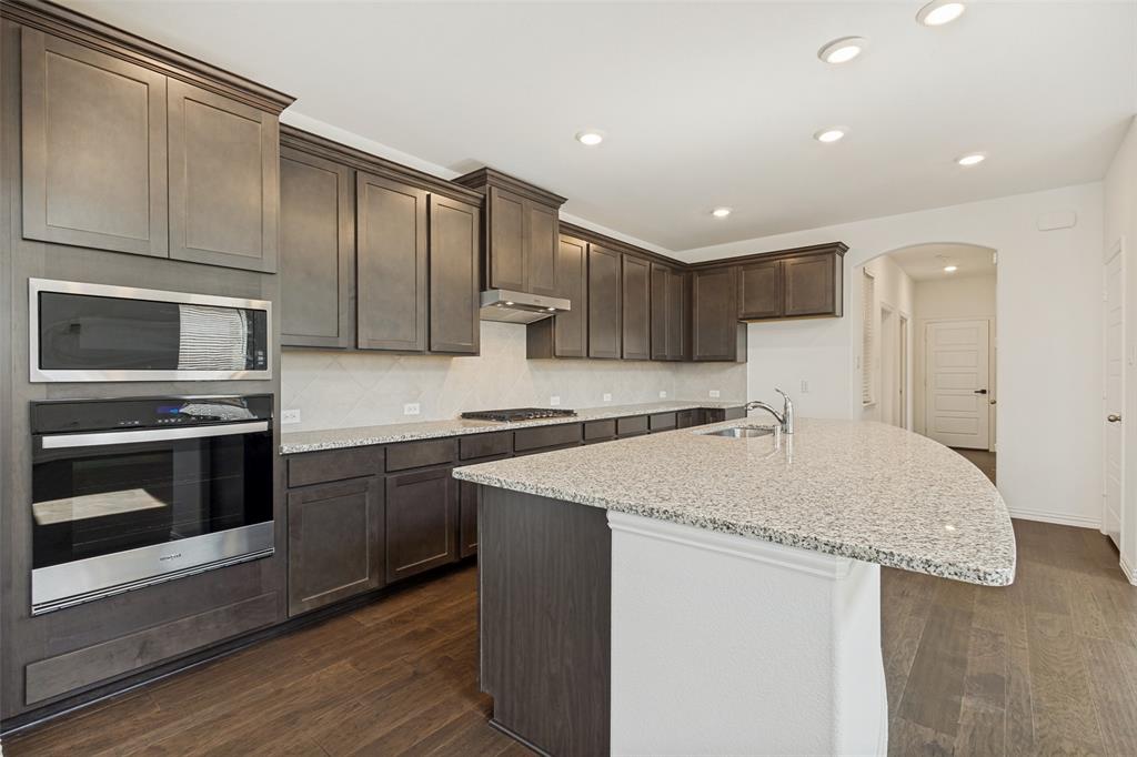 1448 Sun Gdn Way Justin, TX 76247 - Photo 6 of 15 Kitchen featuring dark wood-finish cabinetry, light speckled countertops, a built-in stainless steel microwave and oven, a gas cooktop, and wood-finish flooring