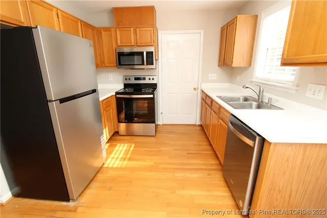 a kitchen with stainless steel appliances a refrigerator a sink a stove a washer dryer and a refrigerator
