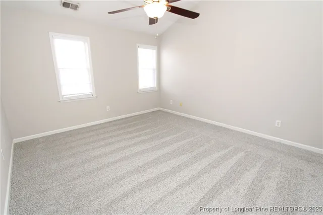 an empty room with a window and a chandelier fan