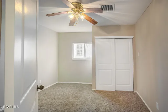 an empty room with a chandelier fan and a window