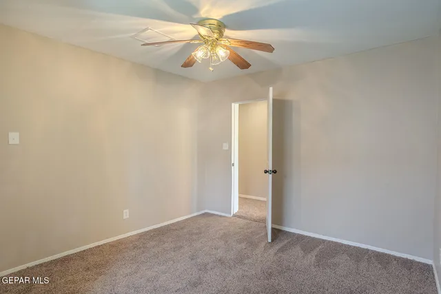 a view of an empty room with window and chandelier fan