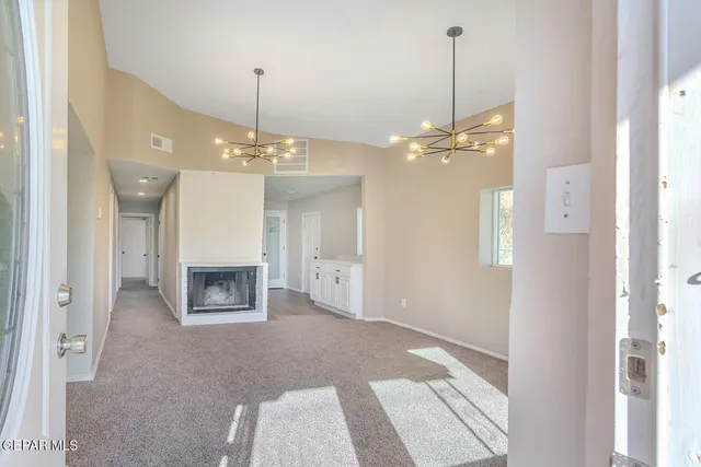 a view of a livingroom with a fireplace a ceiling fan and kitchen view