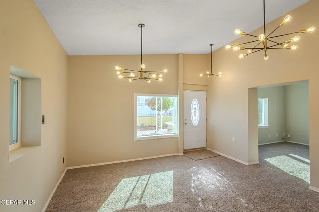 a view of an empty room with window and chandelier
