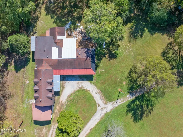 an aerial view of residential house with outdoor space and trees all around