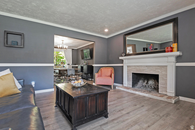 3310 Creek Road Salt Lake City, UT 84121 - Photo 11 of 49 Living area featuring a white mantel fireplace with stone surround, wood-finish flooring, two-tone wall treatment, crown molding, and recessed lighting