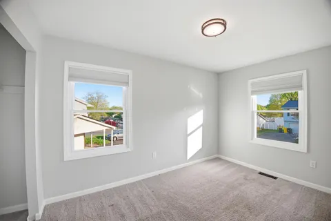 an empty room with windows and mirror