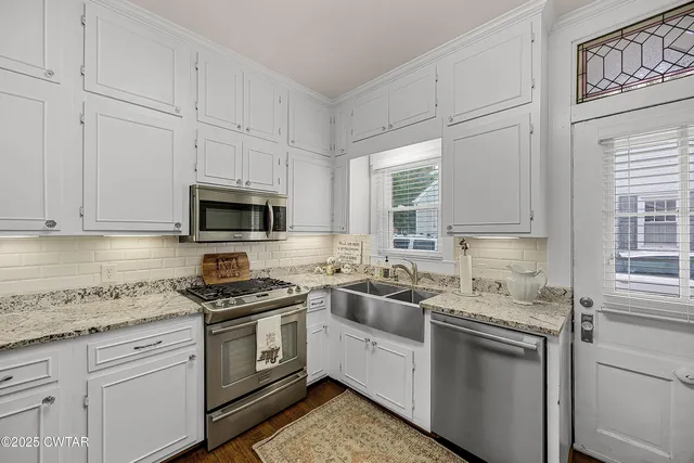 a kitchen with white cabinets stainless steel appliances and sink
