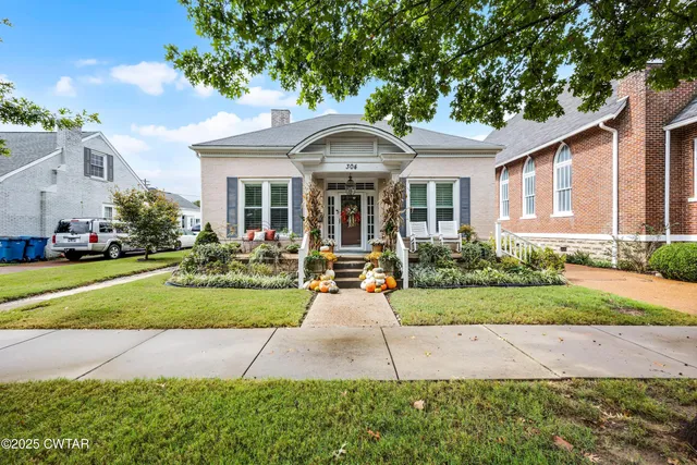 a front view of a house with yard and green space