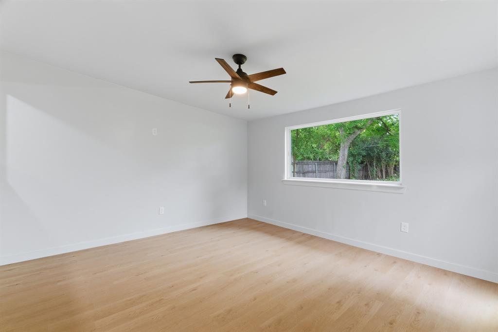 507 Country Club Road Cleburne, TX 76033 - Photo 19 of 39 Bright room featuring wood-finish flooring, a large horizontal window, a ceiling fan with integrated lighting, and neutral wall tones