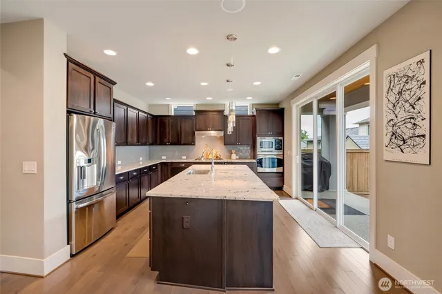 a large kitchen with stainless steel appliances kitchen island a large counter top and a refrigerator