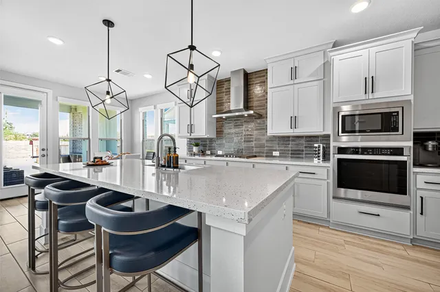 a kitchen with stainless steel appliances a stove a sink a microwave a dining table and chairs