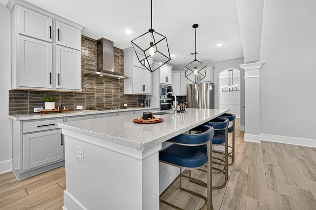 a kitchen with stainless steel appliances kitchen island granite countertop a wooden floor and white cabinets