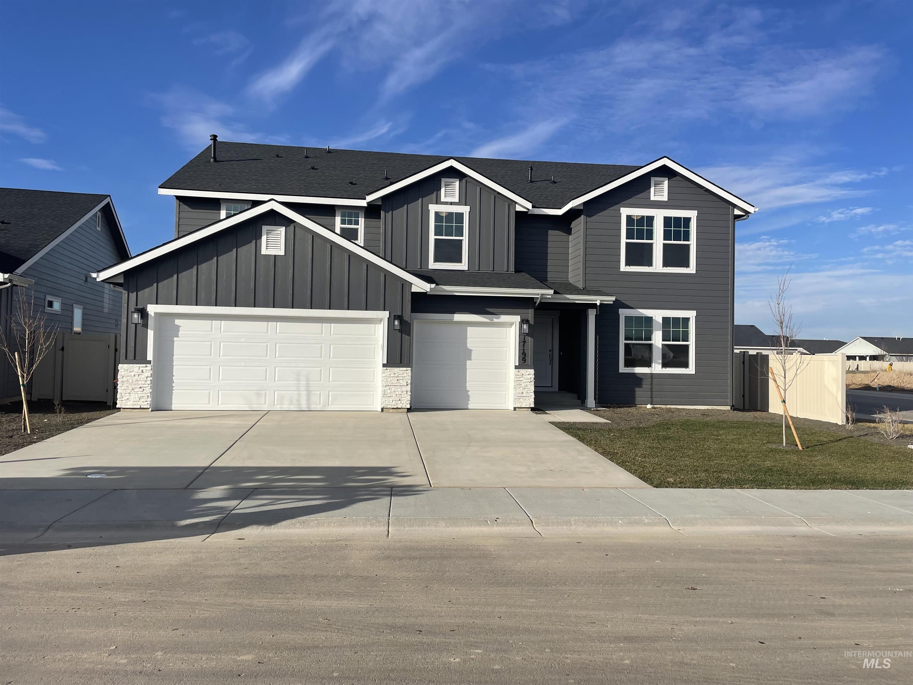 View of front of home featuring board and batten siding, concrete driveway, and stone siding