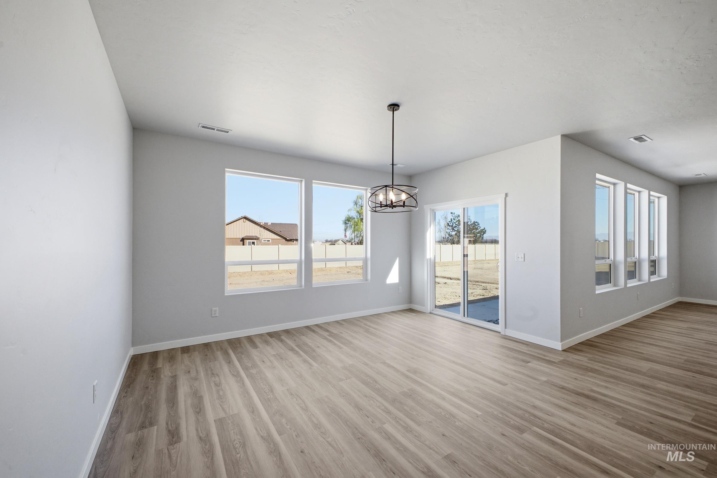 13633 Redway Court Caldwell, ID 83607 - Photo 7 of 29 Unfurnished dining area featuring suspended lighting, light wood-style flooring, and healthy amount of natural light