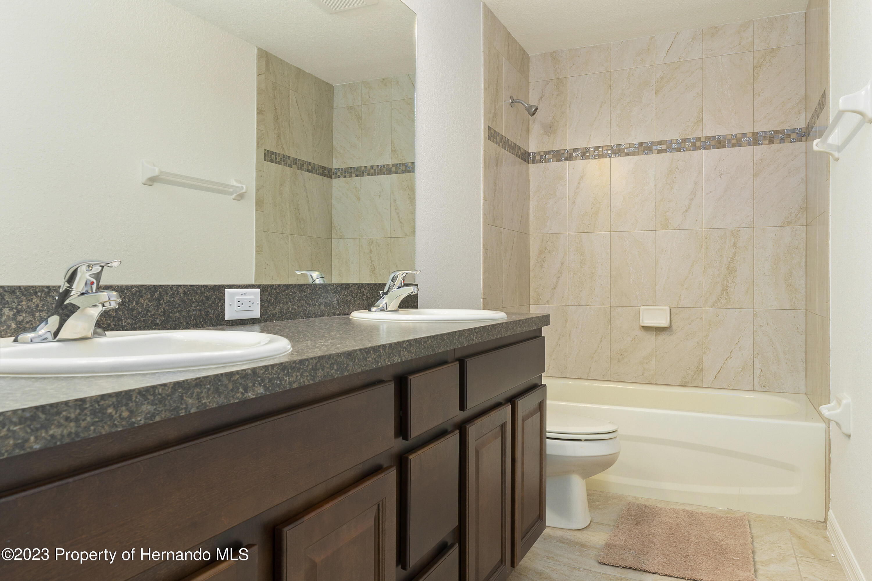 8433 Nightingale Road Weeki Wachee, FL 34613 - Photo 18 of 23 a bathroom with a granite countertop sink a toilet and shower
