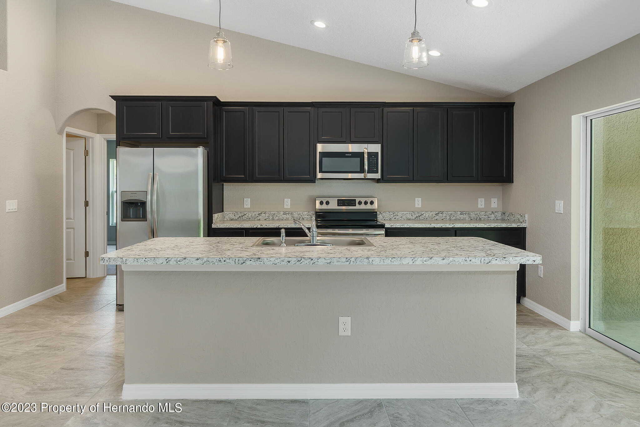 8433 Nightingale Road Weeki Wachee, FL 34613 - Photo 4 of 23 a kitchen with kitchen island stainless steel appliances a sink and a refrigerator