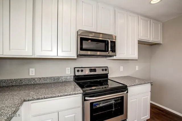 a kitchen with granite countertop white cabinets stainless steel appliances and a sink