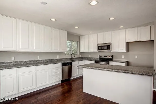 a kitchen with granite countertop white cabinets sink and stainless steel appliances
