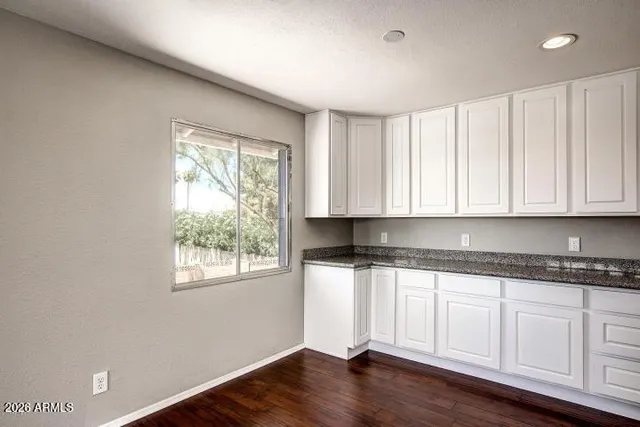a kitchen with granite countertop white cabinets and wooden floor
