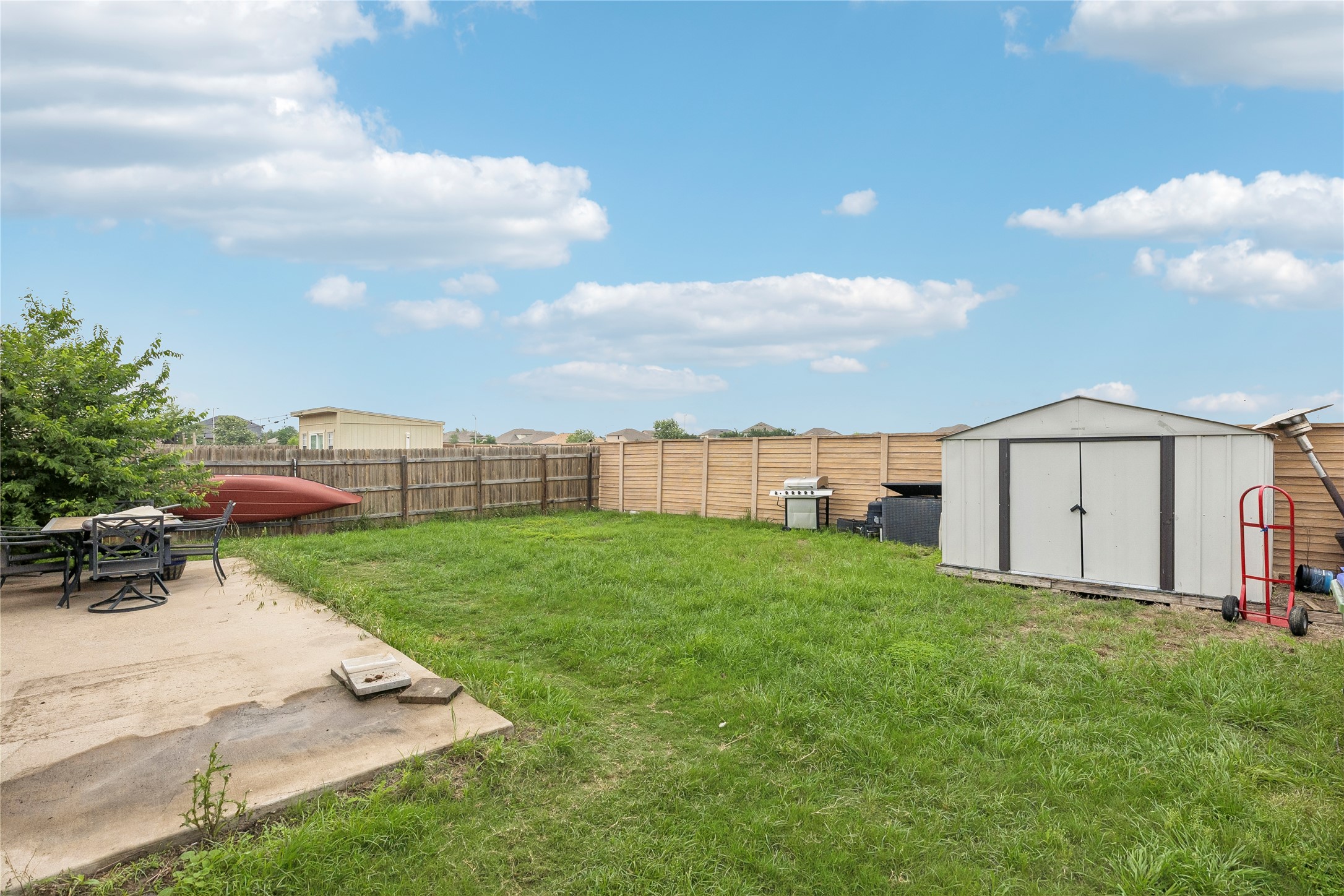 14409 Estuary Road Manor, TX 78653 - Photo 24 of 24 Expansive backyard featuring a concrete patio, a metal storage shed, and a wooden privacy fence