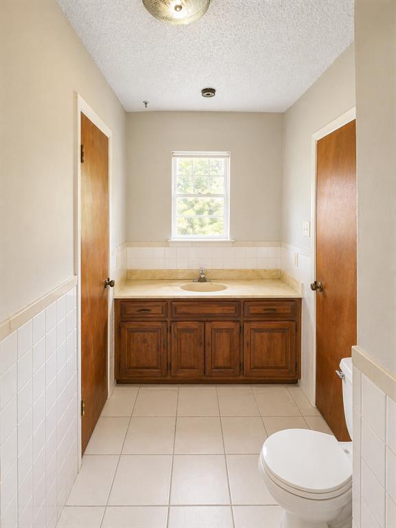 504 Aspen Road Gainesville, TX 76240 - Photo 9 of 11 Bathroom featuring a wood-finish vanity with an integrated sink and light-toned countertop