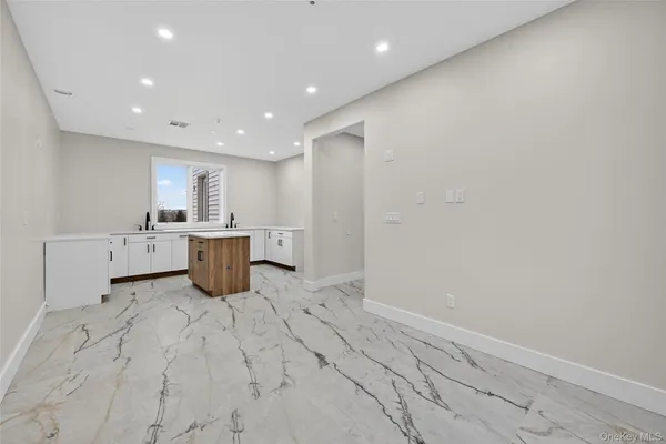 a large white kitchen with a sink dishwasher stove and cabinets
