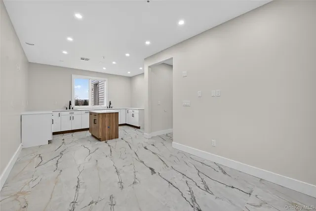 a large white kitchen with a sink dishwasher stove and cabinets