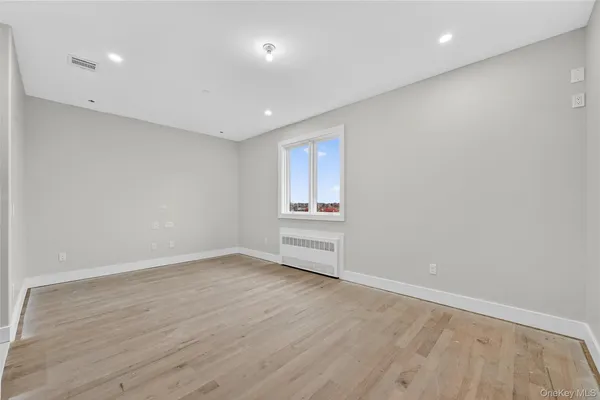 an empty room with wooden floor and natural light