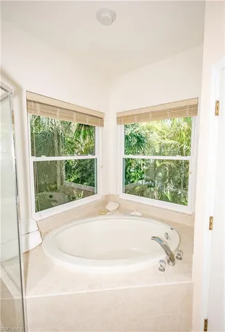 a white bath tub sitting in a bathroom next to a window