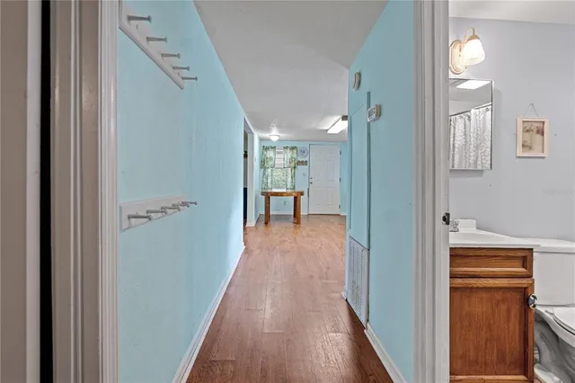 a view of a hallway with wooden floor and a bathroom