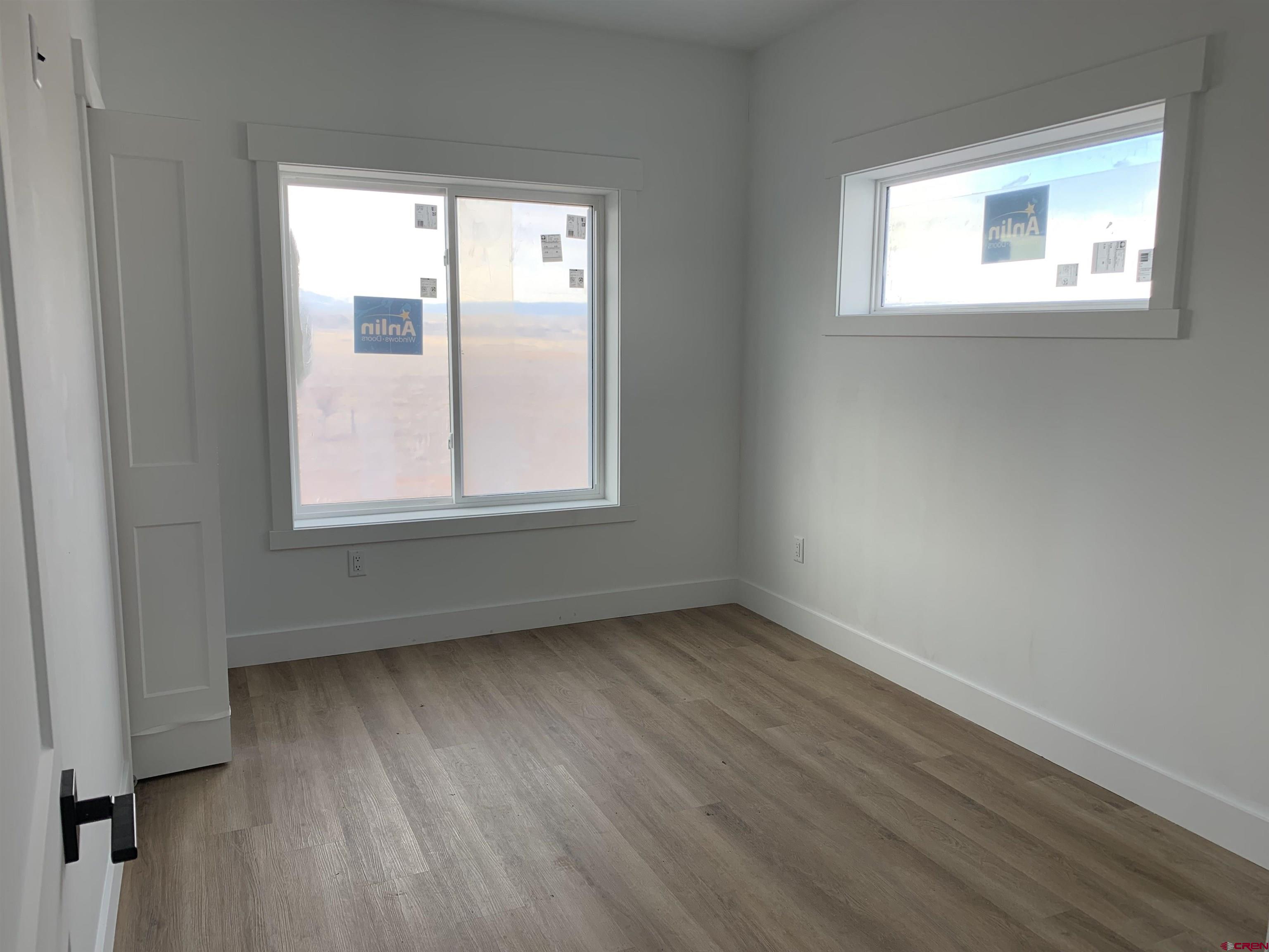 210 Manzano Circle Ignacio, CO 81137 - Photo 6 of 9 an empty room with wooden floor and windows