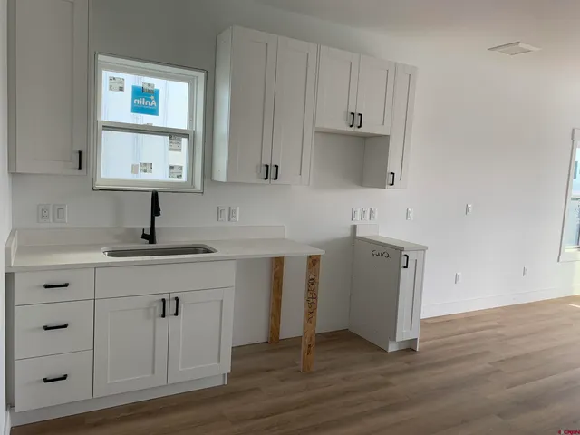 a kitchen with a sink cabinets and wooden floor