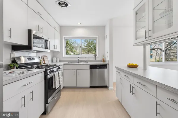 a kitchen with stainless steel appliances white cabinets and wooden floors