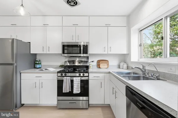 a kitchen with cabinets stainless steel appliances a sink and a window